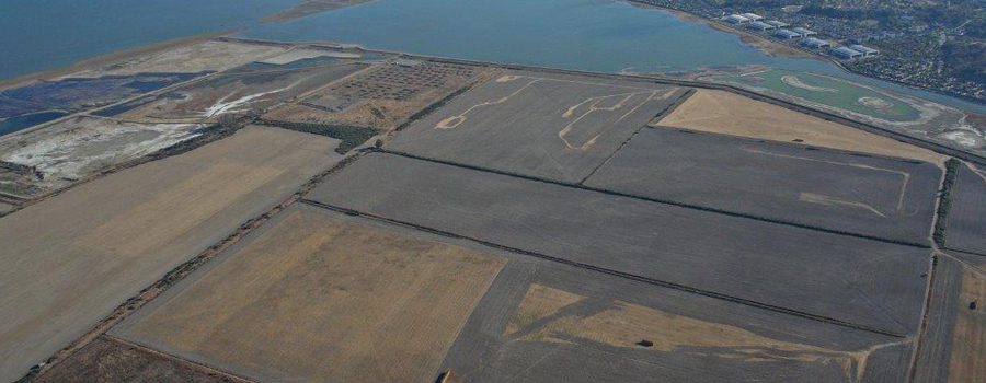 An aerial view of a large field with water in the background.
