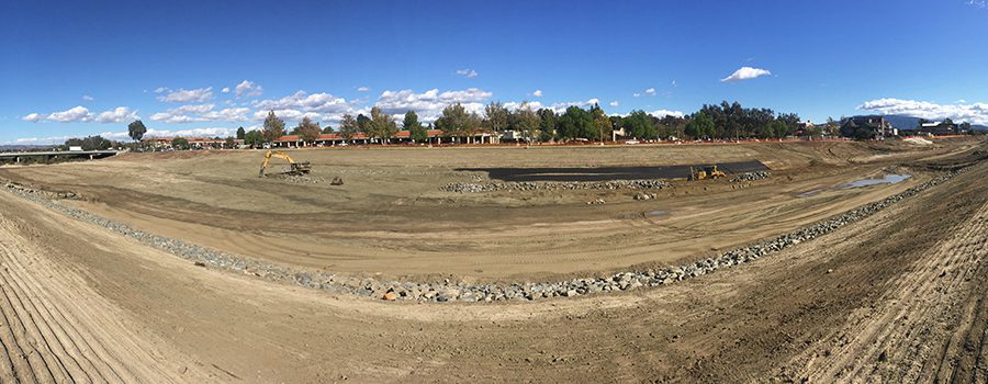 A large dirt field with trees in the background.